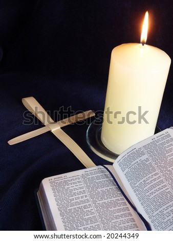 Lit candle with bible open at Palm Sunday story, and palm crosses