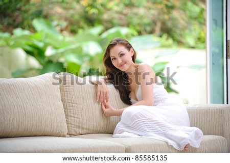 Attractive Asian woman sitting on a sofa in the living room