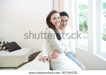 Attractive Happy Asian Couple Sitting next to the window smiling and enjoying