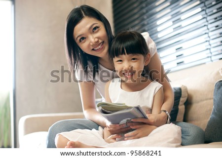 Attractive asian mother reading with her daughter