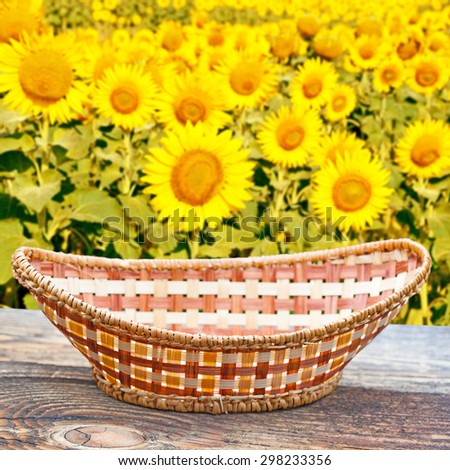 Empty basket on old wooden table.In the background blurred field of sunflowers