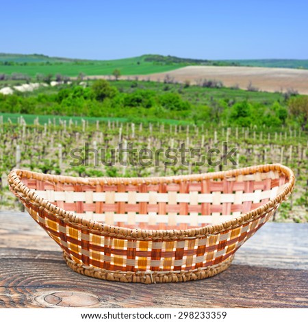 Empty basket on old wooden table.In the background blurred vineyard