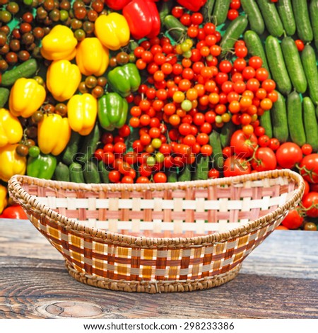 Empty basket on old wooden table.In the background blurred lot of ripe vegetables
