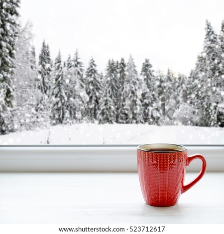 Coffee cup on a window sill. In the background, a beautiful winter forest in snow