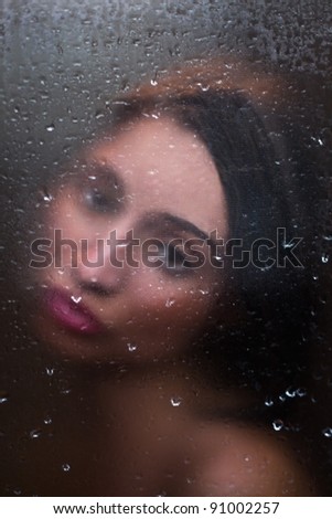 girl with sad eyes behind frosted glass