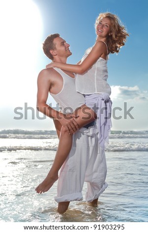 Man and woman falling in love on a beach, surrounded by the sun light