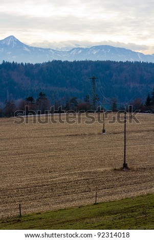 Electricity Towers In An Austrian Landscape In Front Of The Alps