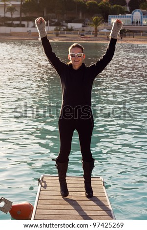 Happy Woman Standing On A Pier With Both Hands In The Air
