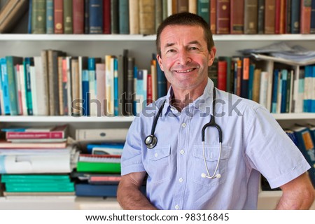 White Doctor In Front Of A Book Shelf Full Of Medical Books