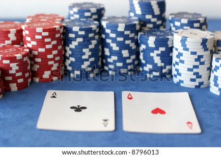 A hand of two aces in front of some poker chips