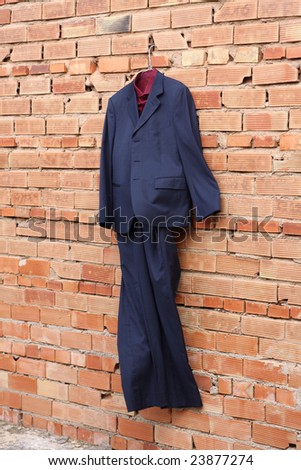 A blue suit is hanging on a brick wall