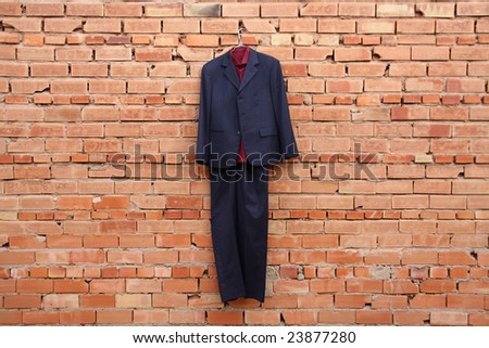 A blue suit is hanging on a brick wall
