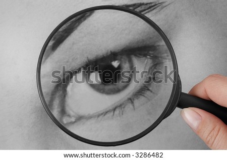 Hand with magnifying glass on human eye.