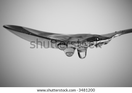 Macro of water splashes in spoon.  Focus on drops. Space for text. Shallow DOF.