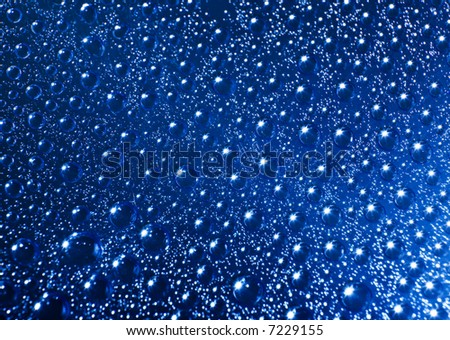 Water drops with stars reflections on blue background. Shallow DOF.