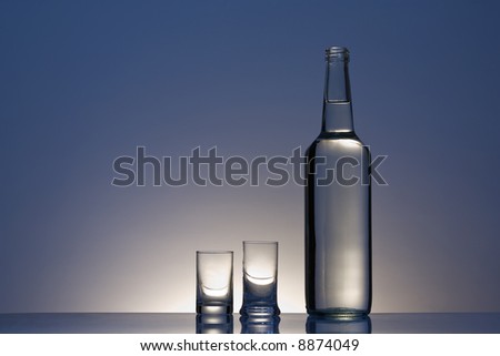 Clear bottle with two vodka glasses against blue gradient background.