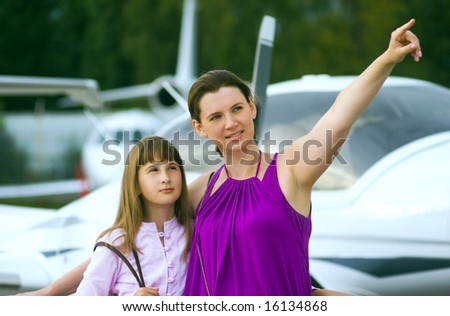 Mother looking daughter to airplane on front view.