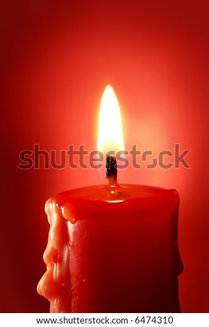 Closeup of burning candle on red background