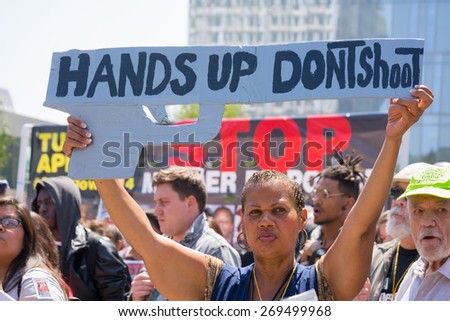 Los Angeles, CA, USA - April 14, 2015:  Woman raising a sign in the form of a gun during Stop Murder by Police. Protest against the brutalization and murdering of black and latino people by police.