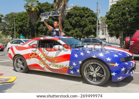 Los Angeles, CA, USA - April 14, 2015:  Woman holding sign next to a car painted in american flag colors during Stop Murder by Police.