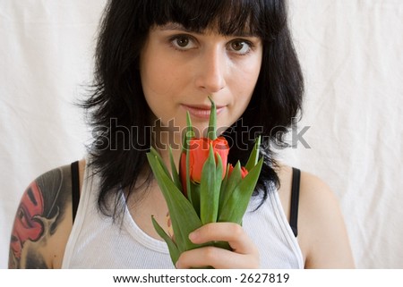 photo of tattooed woman holding red flowers