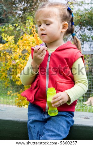 little girl having fun with making soap bubbles