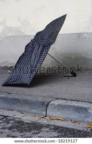 black broken umbrella lying on the pavement.