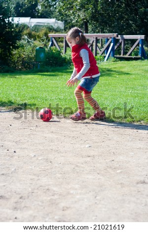 little girl playing football on the green field