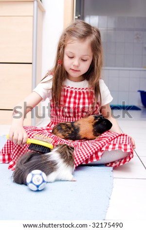 little girl laying with two guinea pigs