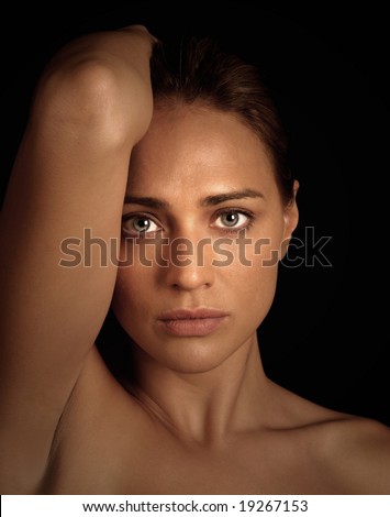 Glamor portrait of a woman with her arm beside her face and the hair straight back on black