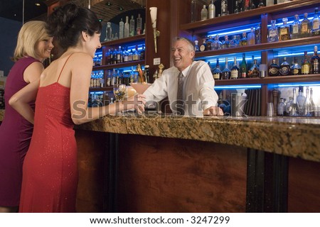 Two ladies talk to a bartender at the bar