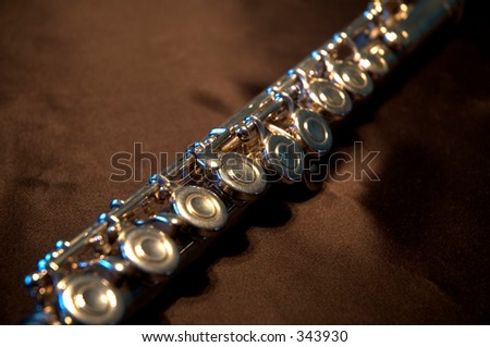 Close up of a golden transverse flute on its case featuring the keys in a blur background