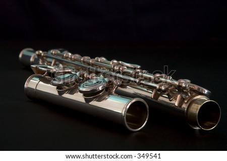 Close up of a silver transverse flute on its case featuring the keys isolated on a black background