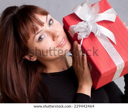Portrait of casual young happy smiling woman hold red gift box with silver ribbon and bow