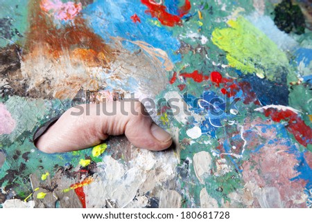 colorful palette full of paint spots and thumb
