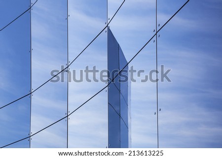 glass panes on facade of trade building reflecting blue sky and clouds