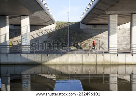 De Meern, The Netherlands, 21 november 2014: man jogs under fly-over near De Meern in The Netherlands along canal