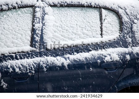 snow fals on door and windshields of blue car