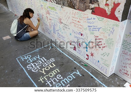 new york city, 11 september 2015: young woman sits on pavement near ground zero in new york city and writes on wall for patriot day