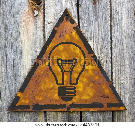 Light Bulb Icon on Weathered Triangular Yellow Warning Sign. Grange Background.
