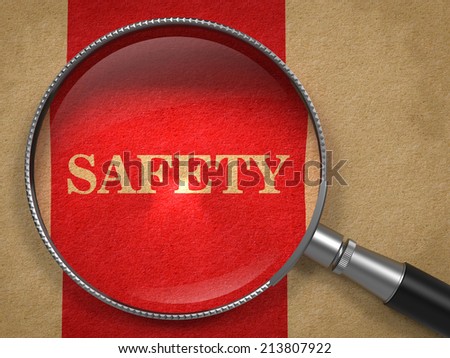 Safety through Magnifying Glass on Old Paper with Red Vertical Line.