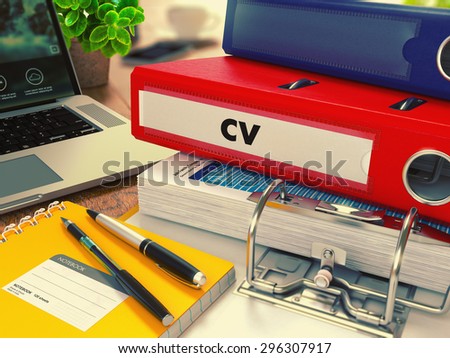Red Office Folder with Inscription CV - Curriculum Vitae - on Office Desktop with Office Supplies and Modern Laptop. Business Concept on Blurred Background. Toned Image.