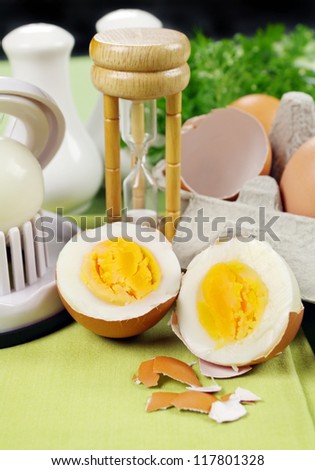 Cracked boiled egg with an egg timer ready to serve.