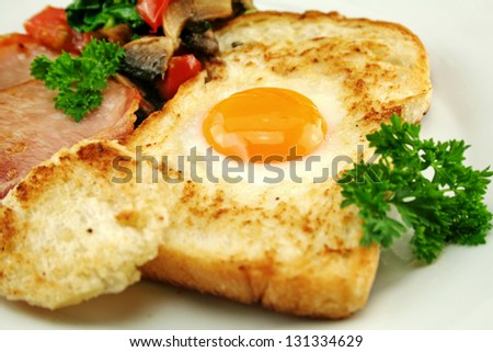 Egg embedded in toast with bacon, mushrooms, spinach and tomatoes.