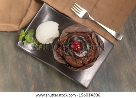 Top view of a delicious chocolate mudslide muffin with a scoop of ice cream with a cherry on top.