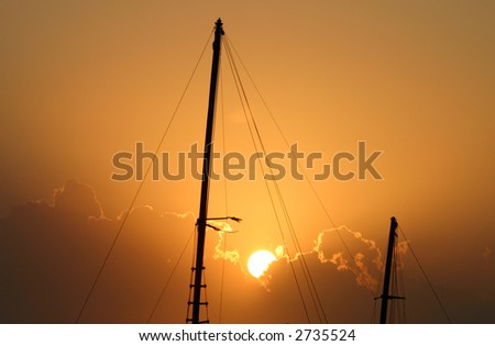 Early morning sun breaks over old yacht masts.