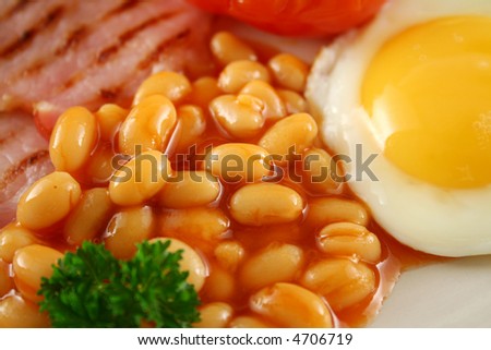 Breakfast of grilled bacon, tomato, egg and baked beans.