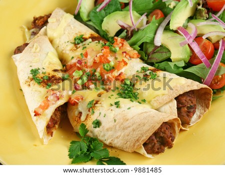 Beef and red kidney bean enchiladas with cheese and salad.