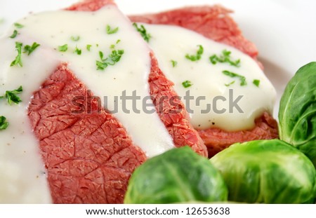 Delicious sliced corn beef with white sauce and vegetables.