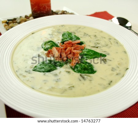 Creamy spinach soup with crispy bacon and spinach leaves.